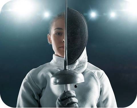 Un escrimeur en uniforme blanc tient un fleuret à la verticale. La moitié de son visage est visible sous un masque grillagé. Les lumières vives du stade brillent en arrière-plan, créant une atmosphère dramatique et concentrée.